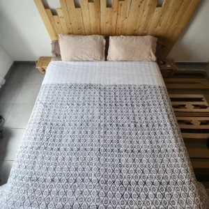 Couvre lit en coton indien blanc avec motif gris présenté sur un lit