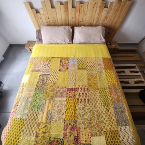 couvre-lit indien artisanal style kantha de couleur jaune présenté sur un lit