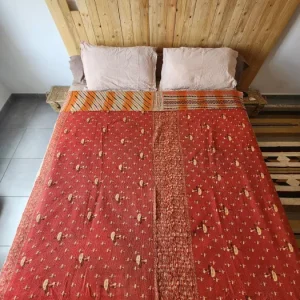 couvre-lit coton réversible fait main en Inde vue face rouge imprimé floral présenté sur un lit