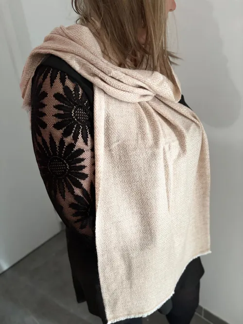 Écharpe en cachemire crème rosé avec motif losange, élégamment portée. Douce et légère, parfaite pour un look chic et intemporel.