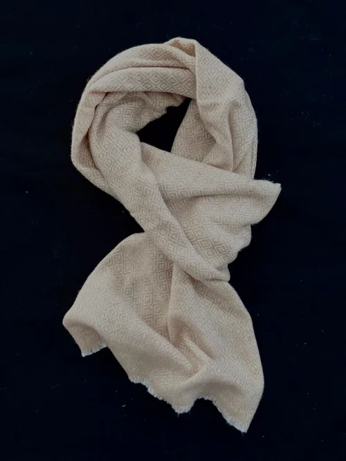 Écharpe en cachemire crème rosé avec motif losange, nouée avec élégance. Douce, légère et raffinée, idéale pour sublimer toutes les tenues.