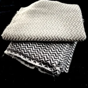 Écharpe en cachemire motif chevron, tissée à la main en Inde. Présenté en noir et beige, son tissage fin allie chaleur et raffinement pour un style unique.