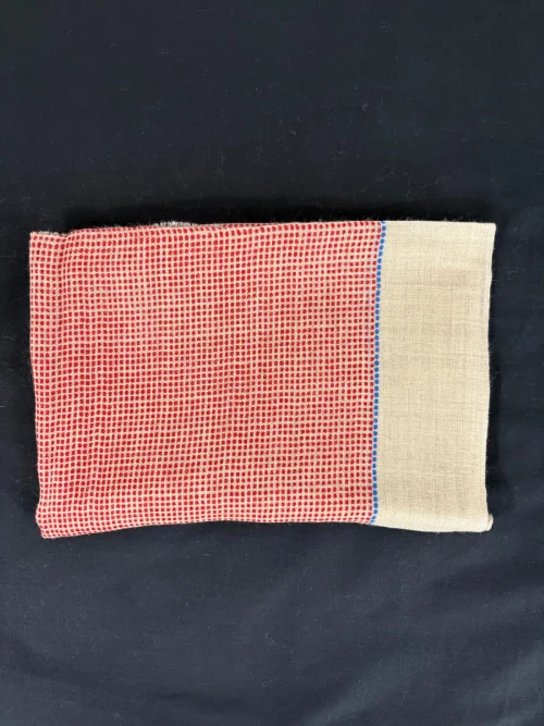 étole cachemire motif quadrillé rouge présentée pliée sur fond noir