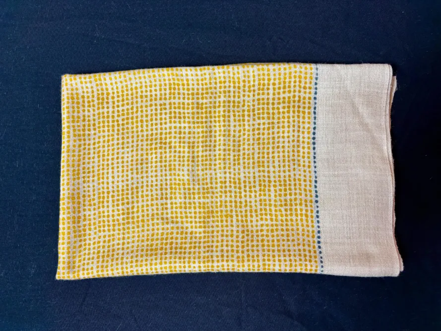 étole cachemire motif quadrillé jaune présentée pliée sur fond noir