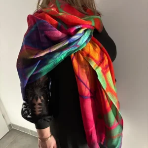 Étole en cachemire multicolore portée sur une femme, mettant en valeur sa douceur et ses couleurs éclatantes.