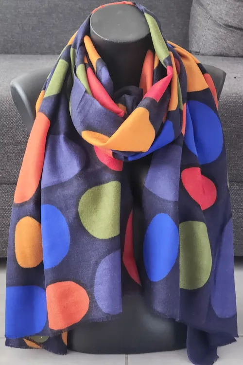 Étole cachemire multicolore Cercles de Vie – étole portée enroulée autour du cou, motifs ronds rouges, orange, bleus, verts, sur fond noir.