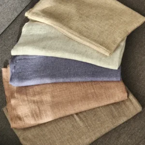 Assortiment d'étoles cachemire unies pliées en éventail (bleu, crème, gris, gris clair, marron) sur fond noir, présentation des différentes couleurs disponibles.