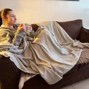 Femme détendue sur un canapé, enveloppée dans un plaid en cachemire beige à motifs losange