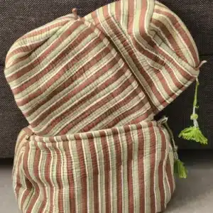 trousse bohème indienne DHAARI fermées, présentant un motif à rayures marron, vert sauge et blanc crème avec des pompons vert anis.