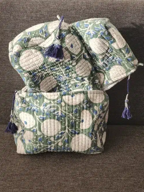 Ensemble de trois trousses toilette coton indiennes bohèmes VANAMALA fermées, présentant un motif floral rétro vert et crème des pompons bleu marine décoratifs.