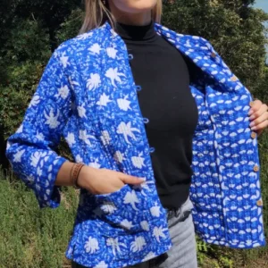 Veste indienne matelassée Nilima en coton bleu avec motifs floraux blancs, réversible avec intérieur à motifs géométriques, confectionnée à la main selon la technique traditionnelle du khanta. Portée par mannequin féminin