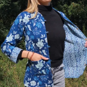 Veste coton matelassée Indira en coton bleu avec motifs floraux blancs, réversible avec intérieur à motifs plus discrets, confectionnée à la main selon la technique traditionnelle du khanta. Portée par mannequin féminin